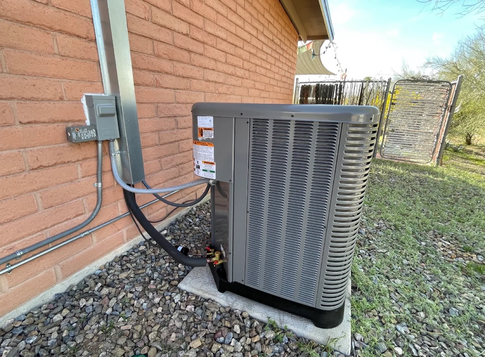 Clean air conditioning condenser beside a brick Tucson home.