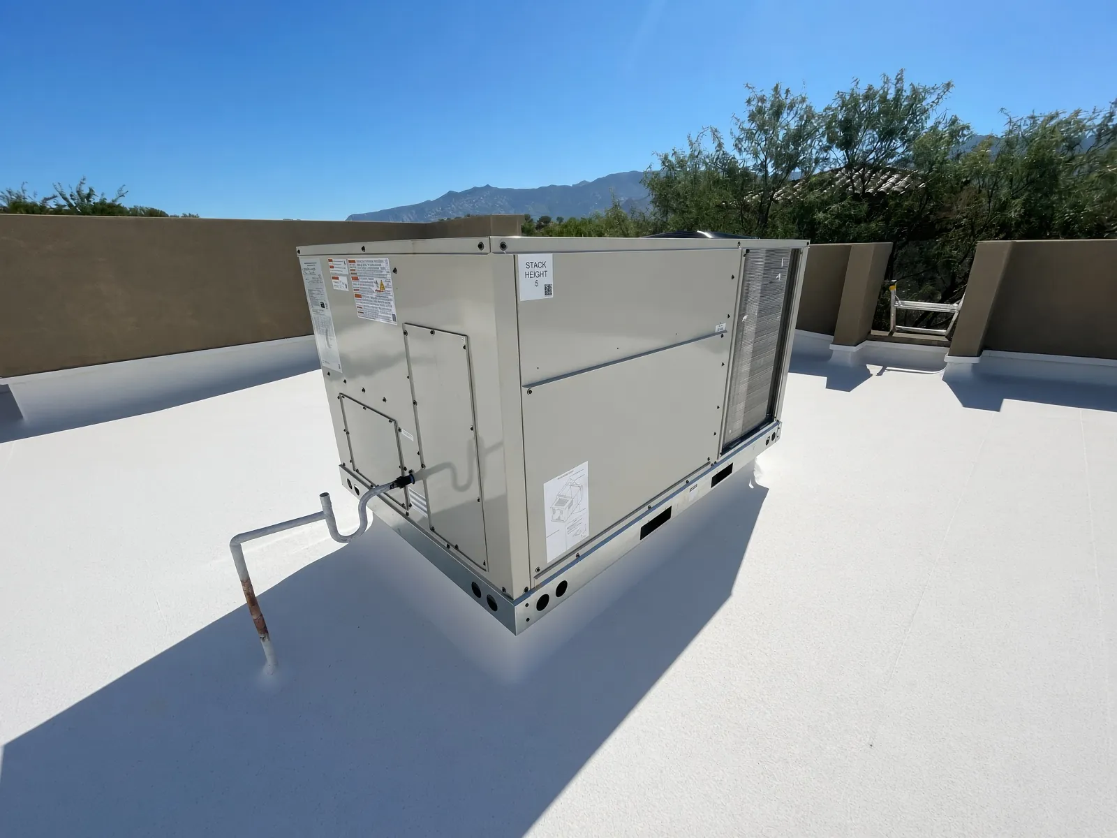 New rooftop package unit installed by Picture Rocks on a Tucson flat roof, with the Catalina Mountains behind.