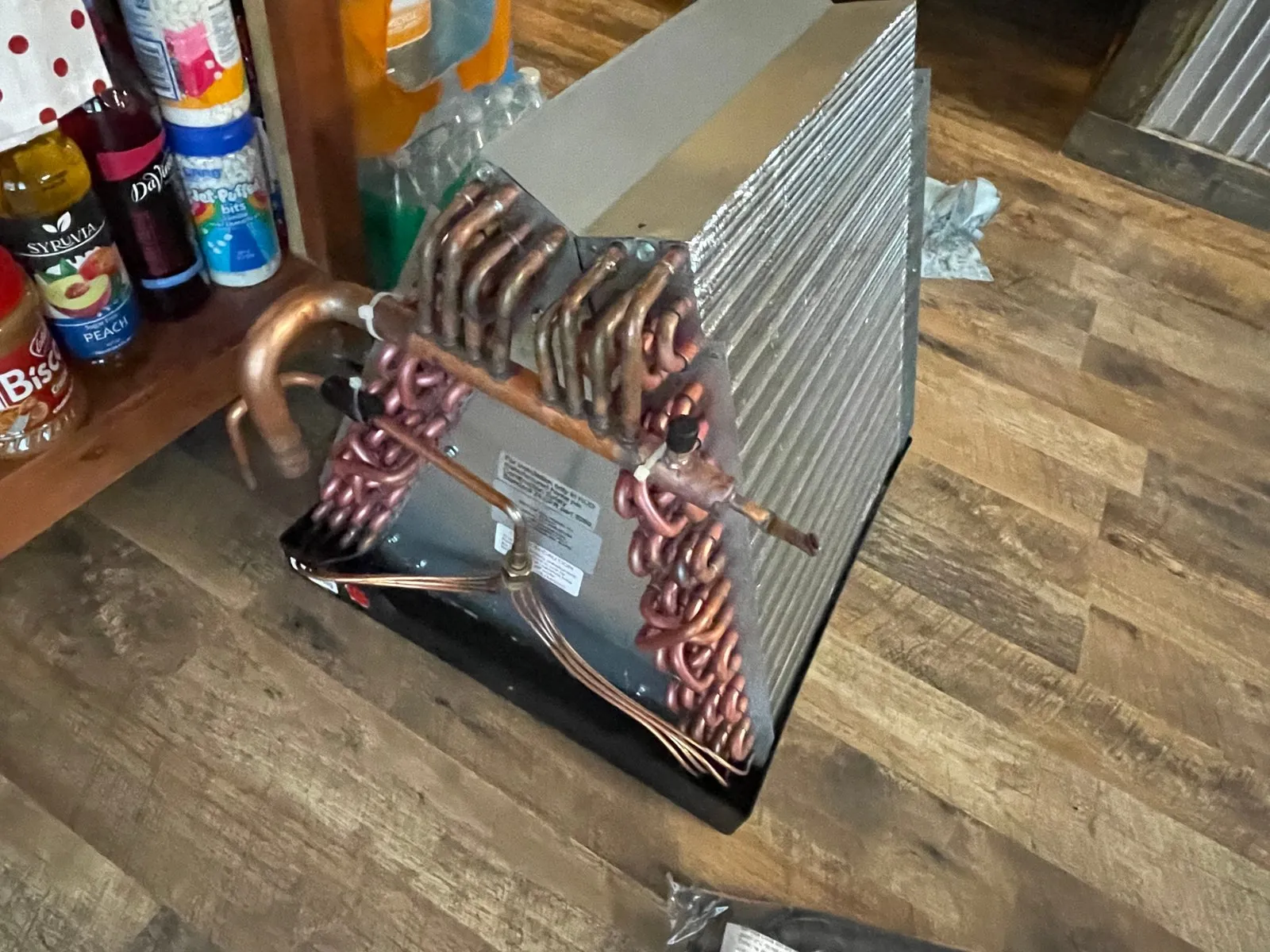 The new evaporator coil with its copper refrigerant connections, photographed on the floor before installation at the Marana home.