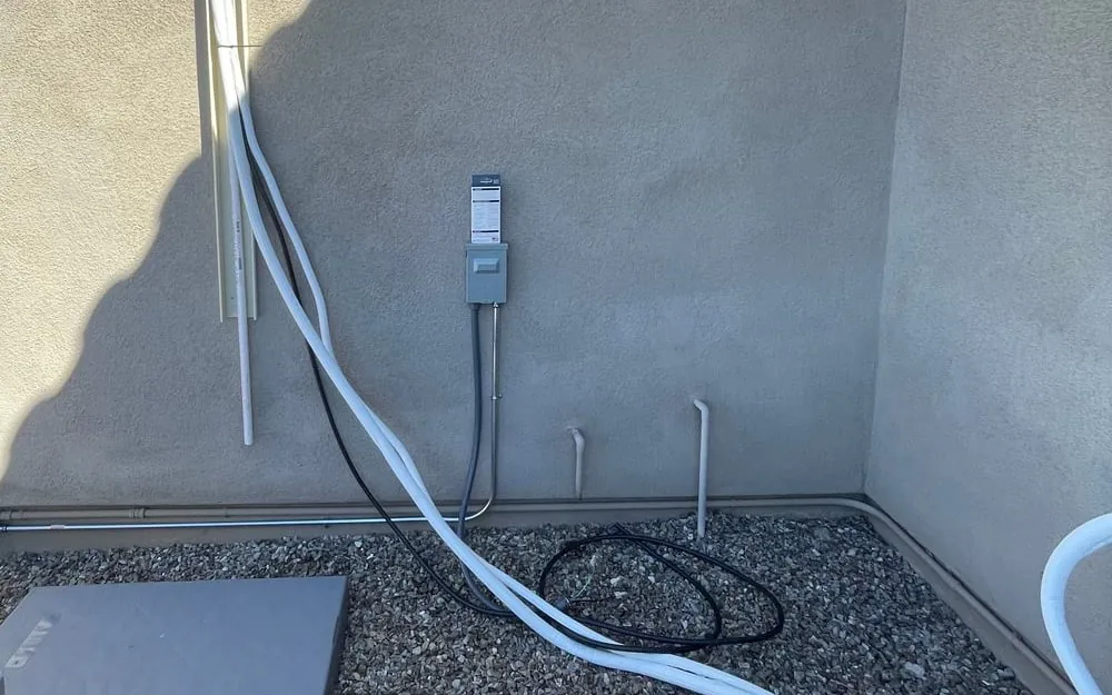 Insulated refrigerant lines coming down the outside wall toward the new pad, before the cover went on.