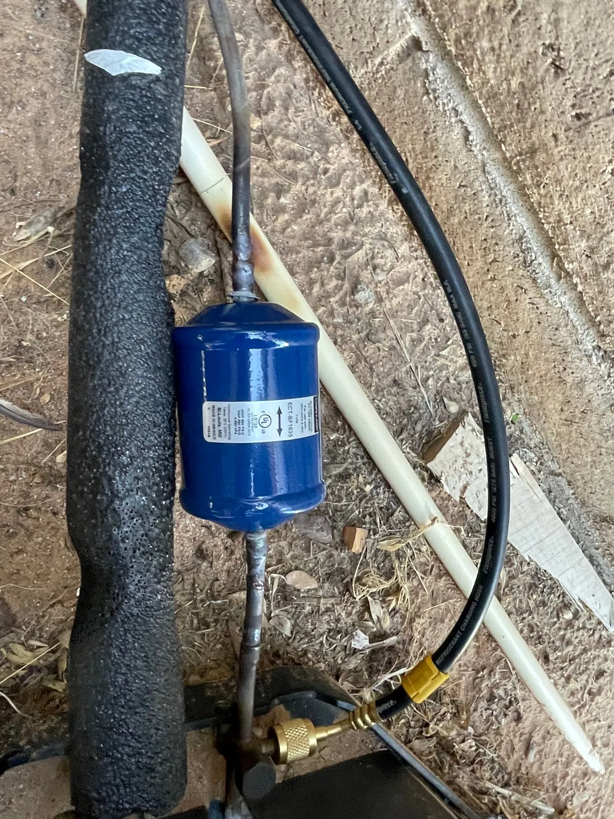 A new blue filter drier brazed into the insulated refrigerant line.