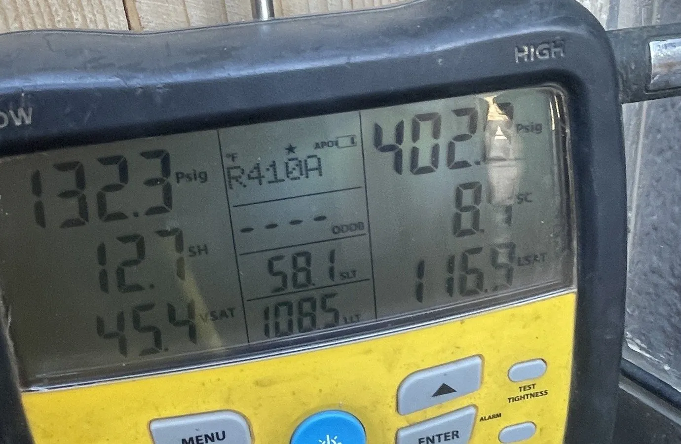 A digital manifold gauge displaying refrigerant pressures, superheat and subcooling after the coil repair.