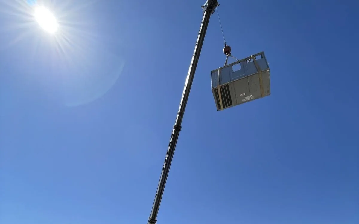The new package unit hanging from a crane above the roof.