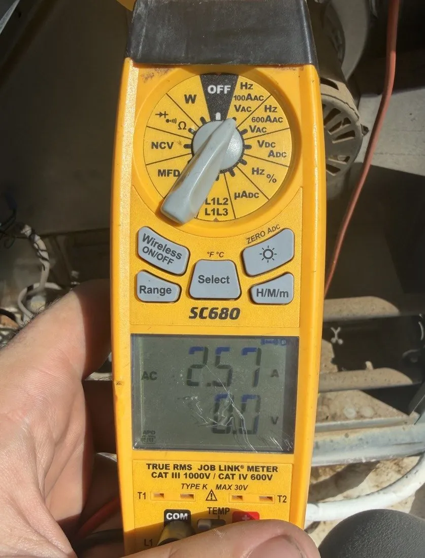 A clamp meter reading current at the rooftop unit during the service visit.