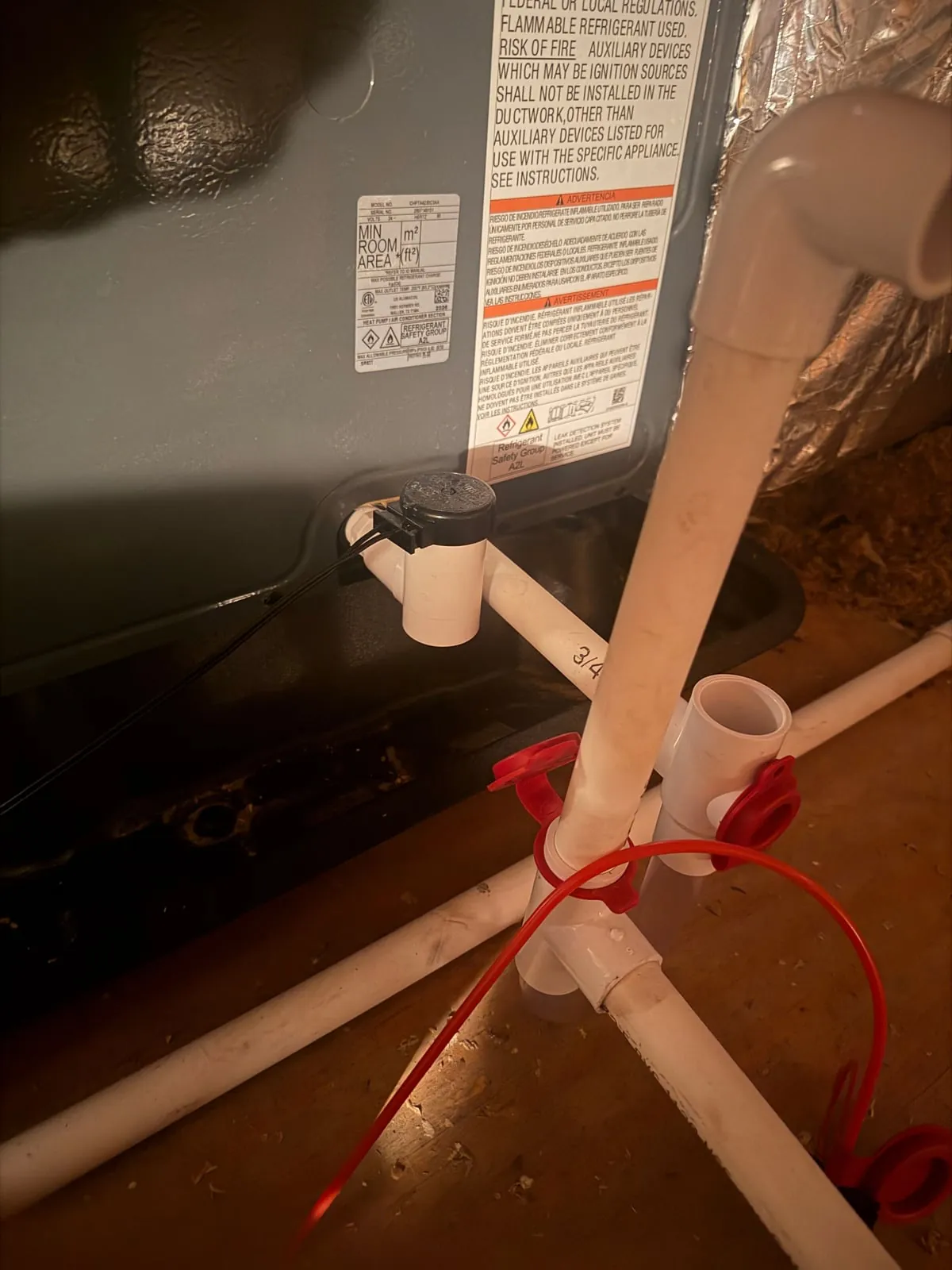 A float switch mounted on the white condensate drain line at the indoor equipment.