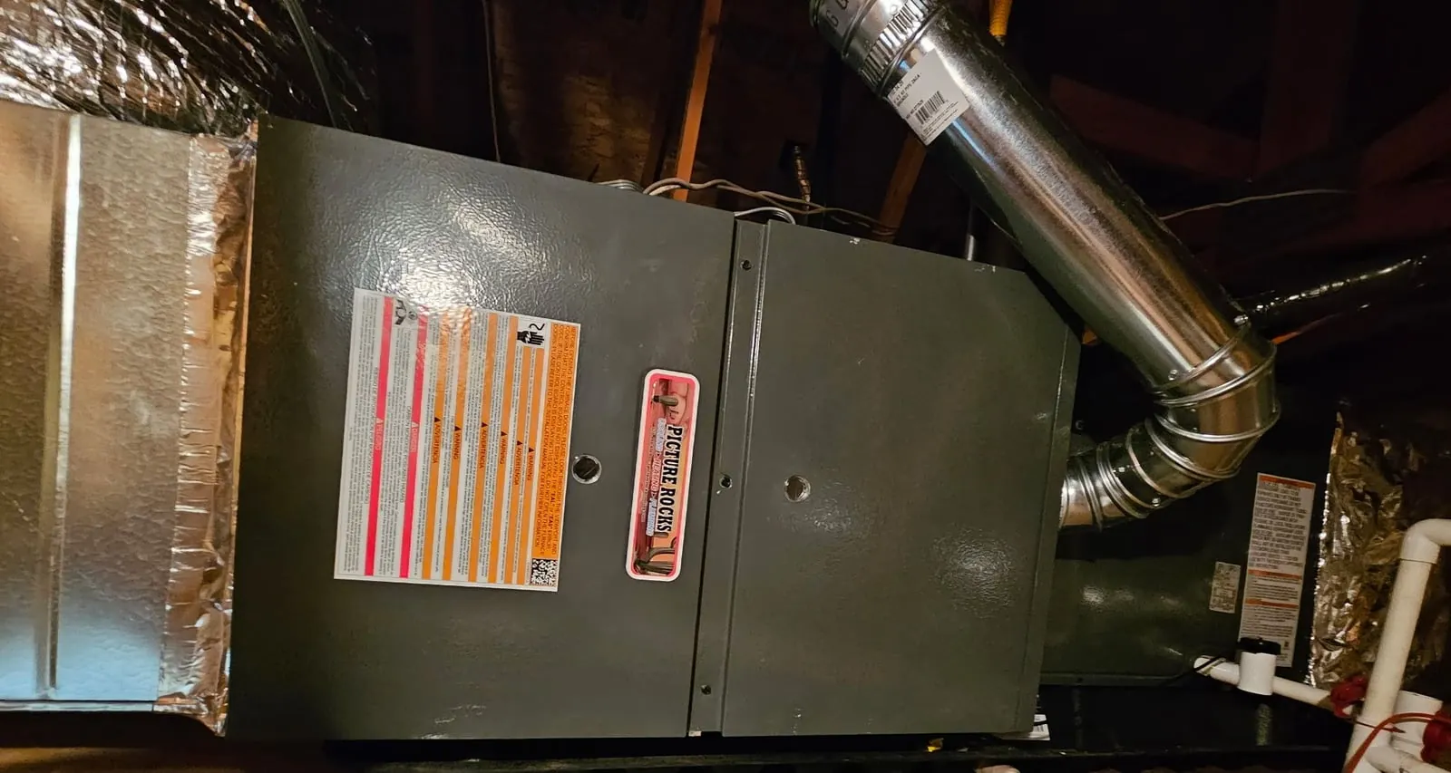 The new gas furnace installed in the attic, with sealed duct connections and its vent pipe.