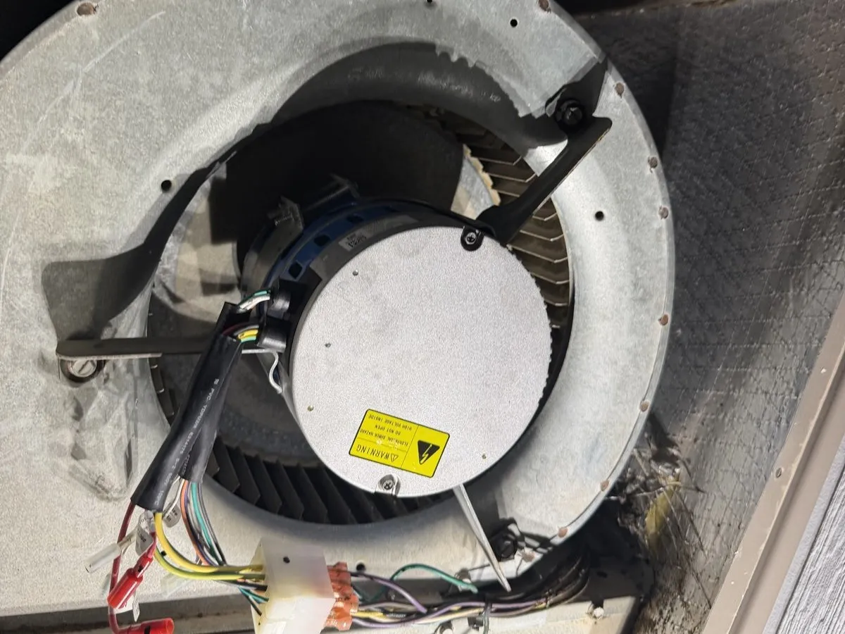 The replacement blower motor mounted inside the blower housing of the heat-pump package unit, wiring harness attached.
